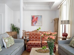 A living room with striped sofas, a patterned sofa, a coffee table with a vase of flowers, and a painting on the wall. - Hommyhome O´Donnell in the heart of Seville (Sevilla)