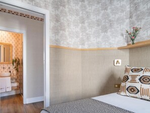 A bedroom with a bed, a nightstand, a mirror, and a wall-mounted shelf with a vase of flowers. - Hommyhome O´Donnell in the heart of Seville (Sevilla)