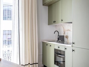 A modern kitchen with a built-in oven, a stainless steel sink, and a marble backsplash. - Hommyhome O´Donnell in the heart of Seville (Sevilla)
