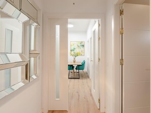 A hallway with mirrored doors, a dining area with a table and chairs, and a painting on the wall. - Hommyhome San Esteban 001 (Sevilla)
