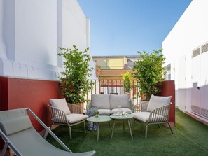 A courtyard with a seating area, a small table, and two potted plants. - Hommyhome San Esteban 001 (Sevilla)