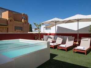 A rooftop pool area with lounge chairs and umbrellas. - Hommyhome San Esteban 001 (Sevilla)