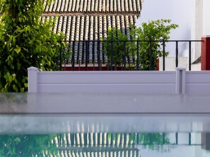 Ein Schwimmbecken mit einem gefliegelten Dach und einem weißen Geländer im Vordergrund.