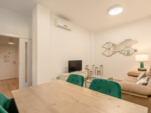 A modern living room with a dining table, green chairs, a sofa, a TV, and decorative mirrors. - Hommyhome San Esteban 001 (Sevilla)