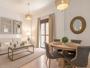 A modern living room with a sofa, coffee table, dining table, and chairs. - Hommyhome San Esteban 101 (Sevilla)