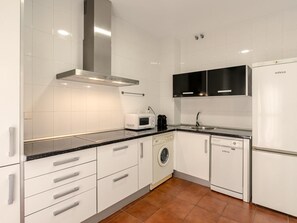 A modern kitchen with white cabinetry, a stainless steel range hood, a microwave, a coffee maker, a washing machine, and a dishwasher. - Hommyhome San Esteban 101 (Sevilla)