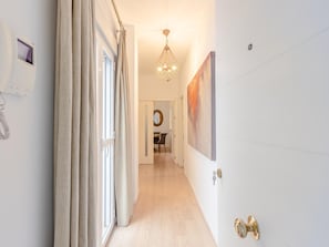 A hallway with a door, a light fixture, and a painting on the wall. - Hommyhome San Esteban 101 (Sevilla)