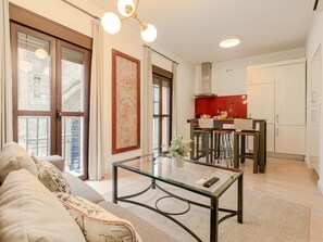 Ein modernes Wohnzimmer mit einem Glastisch, einer Couch und einer Küchenzeile mit roter Spritzschutzwand.