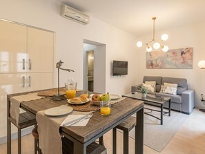 A modern living room with a grey sofa, a coffee table, and a TV mounted on the wall. - Hommyhome San Esteban 102 (Sevilla)