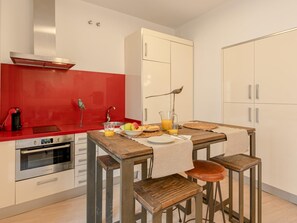 Eine kompakte Küche mit roter Spritzschutzwand, einem eingebauten Ofen und einem Holztisch mit Hocker.