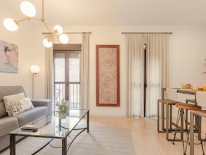 A modern living room with a sofa, coffee table, and a dining area with stools. - Hommyhome San Esteban 102 (Sevilla)