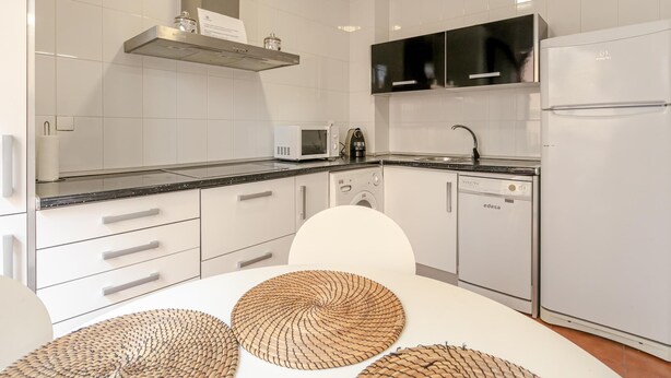 Une cuisine moderne avec des meubles blancs, un four à micro-ondes, une machine à café et un lave-vaisselle.
