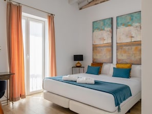 Ein Schlafzimmer mit einem Bett, Vorhängen, einer Lampe und Kunstwerken an der Wand.