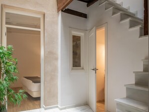 Ein Flur mit einer weißen Tür, einer Treppe und einer Pflanze.