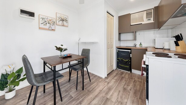 Una cucina moderna con elettrodomestici bianchi, un'area pranzo con tavolo e sedie, e una pianta in vaso.