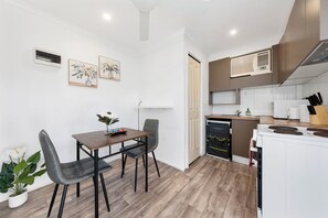Une cuisine moderne avec des appareils électroménagers blancs, un coin repas avec une table et des chaises, et une plante en pot.