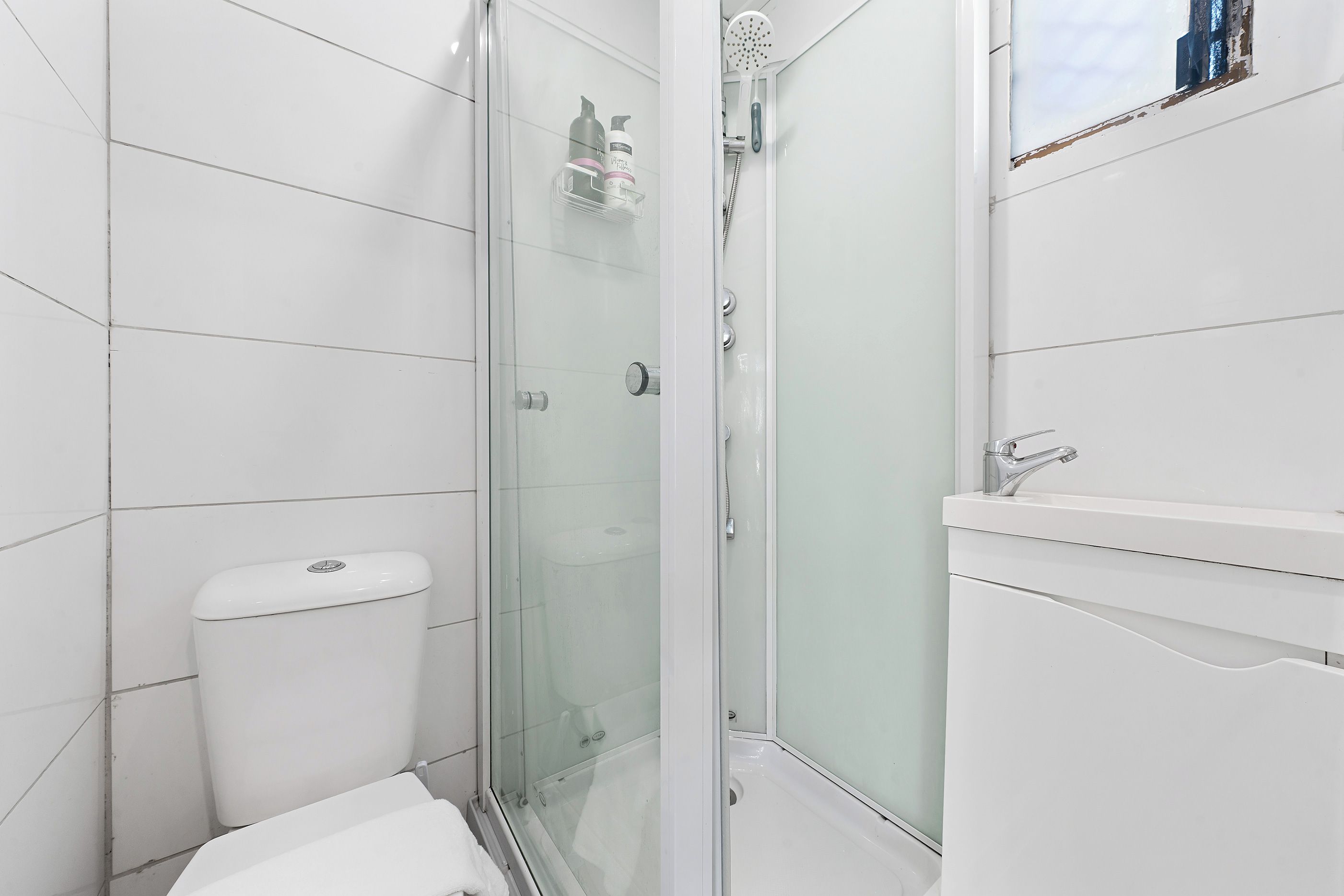 Een badkamer met een douchecabine, toilet en een wastafel met spiegel.