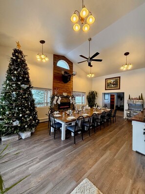 Un comedor con un árbol de Navidad, una mesa de madera, sillas y una chimenea.