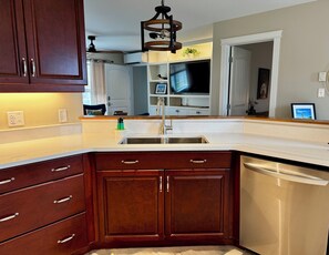 A kitchen with dark wooden cabinets, a stainless steel sink, and a dishwasher.