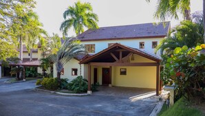 A two-story building with a covered entrance, surrounded by lush greenery and palm trees. - Villa With Private Pool and sea View in Samaná (Samaná)