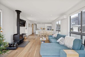 A modern living room with a sofa, a fireplace, a dining area, and a kitchen.