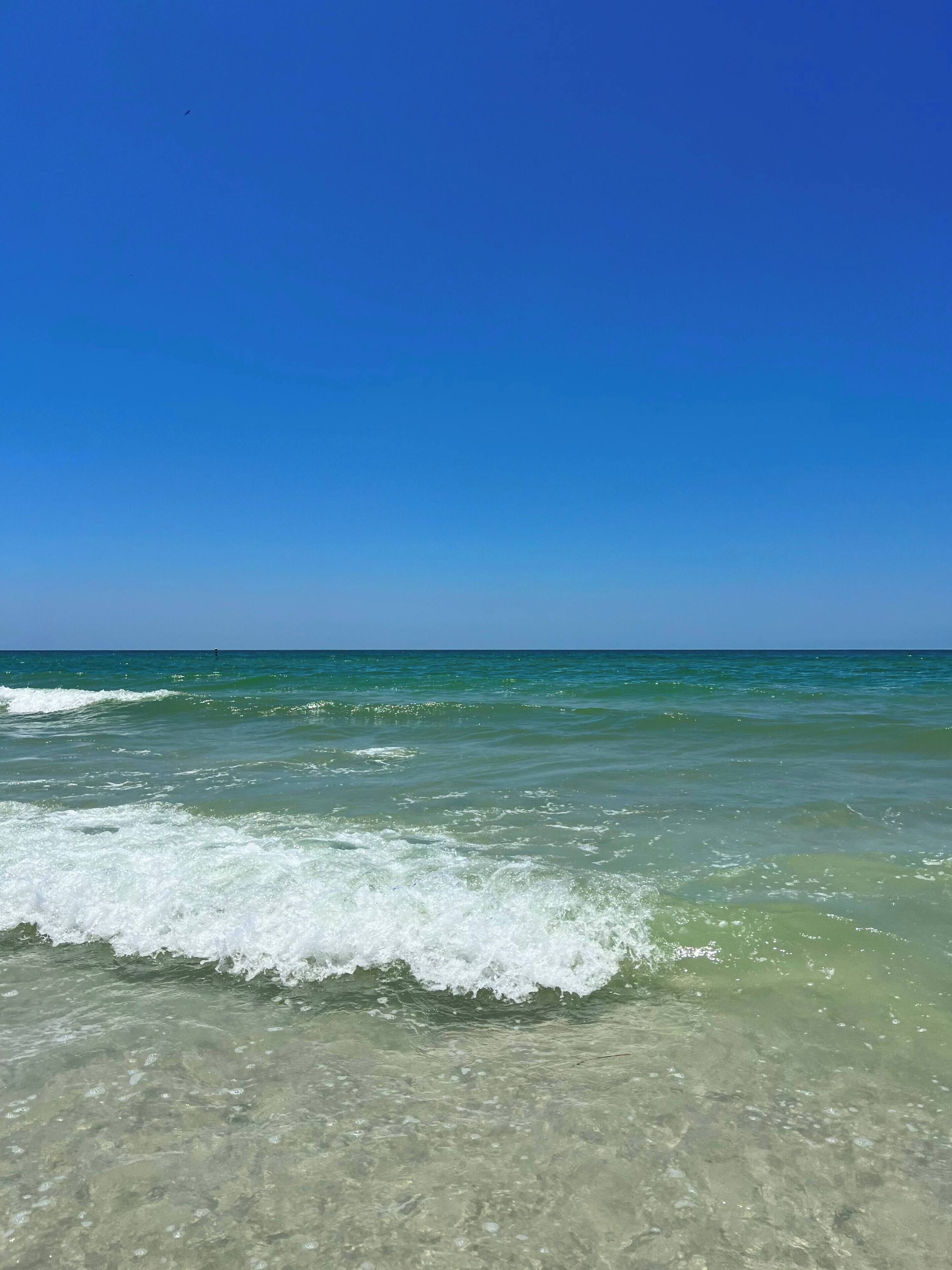 A beach with clear water and waves.
