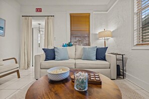 Ein Wohnzimmer mit einem beige farbenen Sofa, einem Holztisch und einer Lampe.