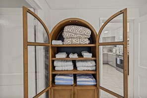 Ein Holzregal in Bogenform mit gefalteten Hand- und Bettwäsche.