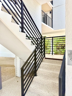 A staircase with black railings leading to a balcony with a view of greenery. - Coastal Retreat, Pool, Marina, Ocean View, FL Keys (Tavernier)