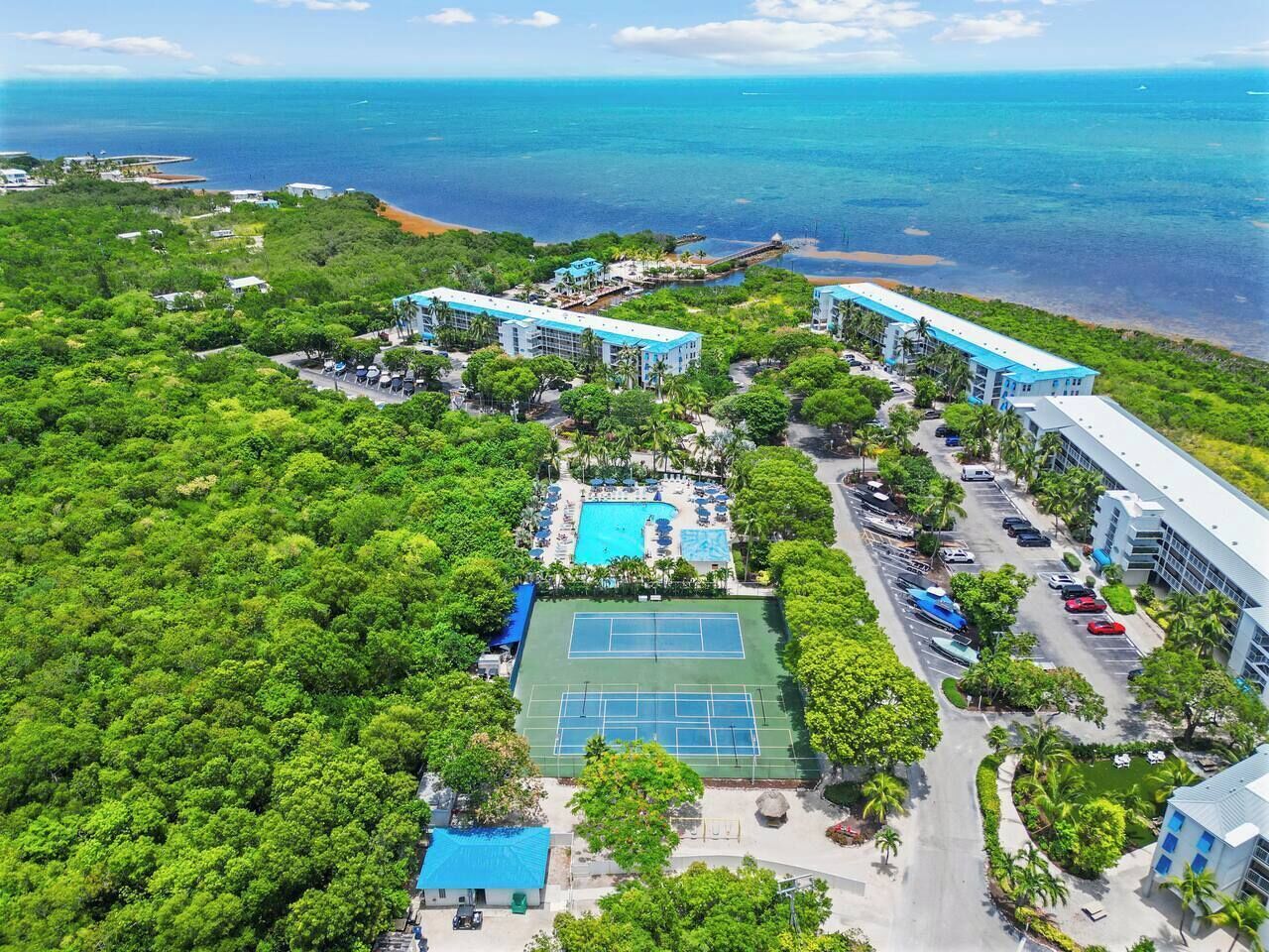 A resort with a tennis court, swimming pool, and beachfront view.