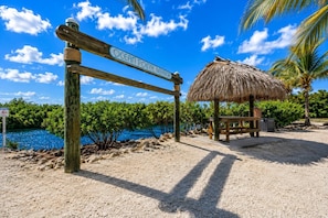 A wooden signpost with 'Ocean Pointe Marina' written on it, a thatched-roof structure, and a bench. - Coastal Retreat, Pool, Marina, Ocean View, FL Keys (Tavernier)