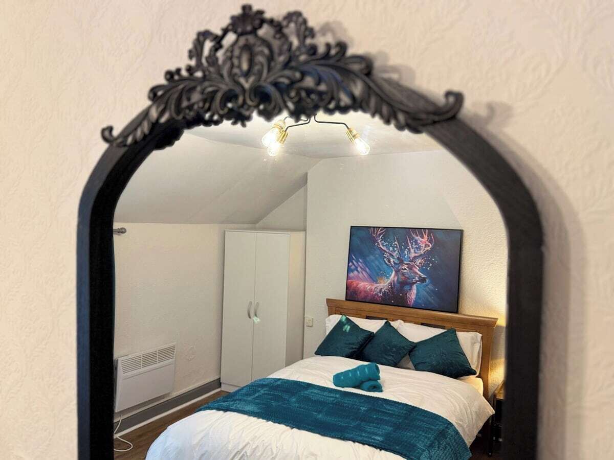 A bedroom with a bed, a headboard, a painting, and a wardrobe.
