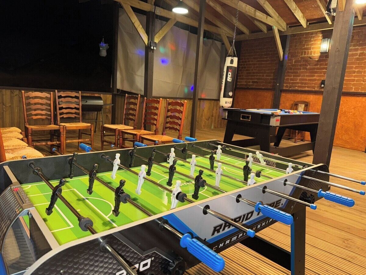A foosball table in a room with brick walls and wooden furniture.