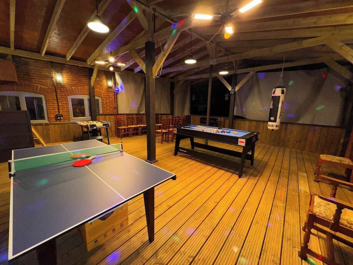 A room with a ping pong table, a foosball table, and a pool table.
