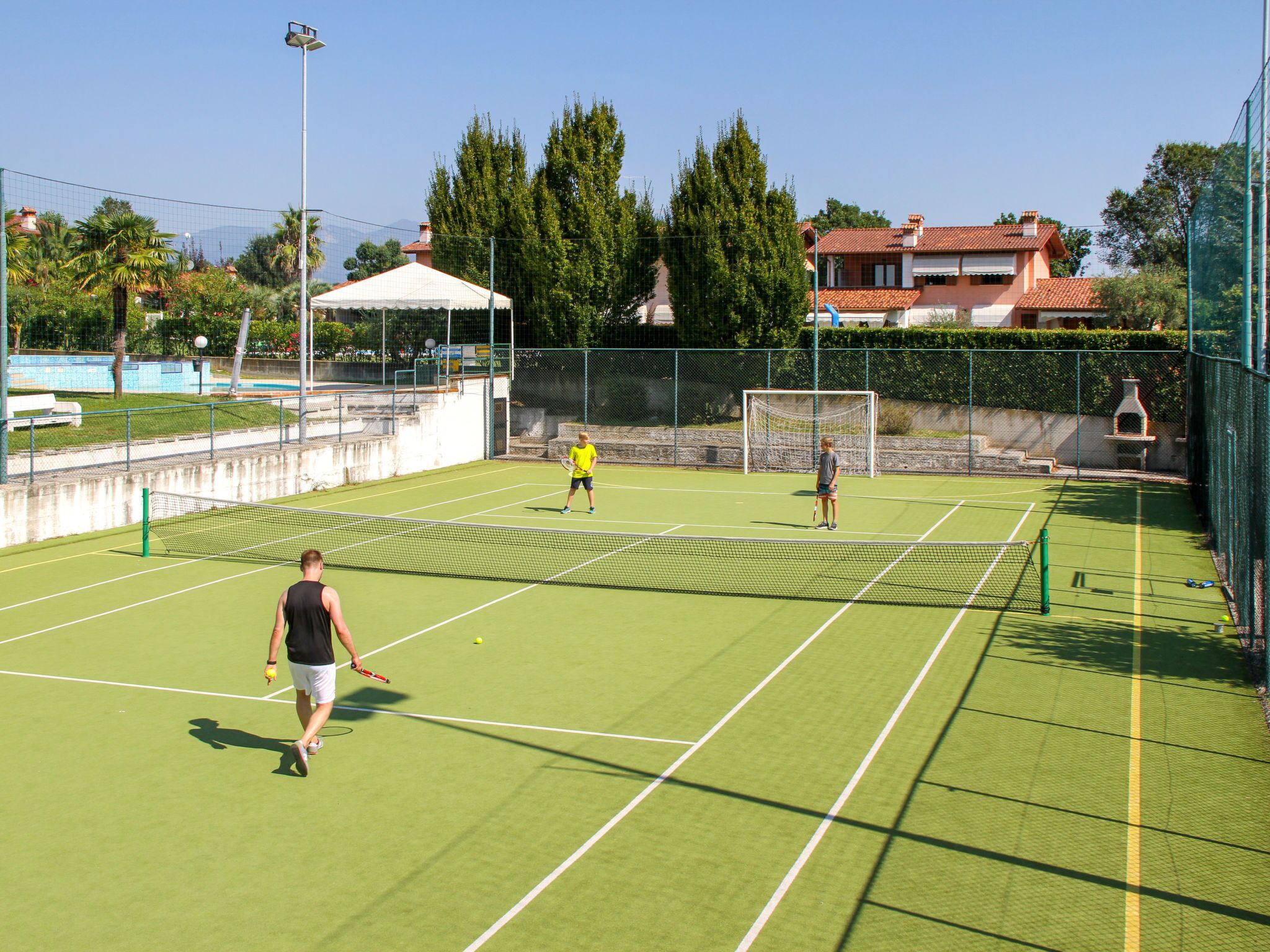 Een tennisbaan buiten met net, een doellat en een paviljoen.