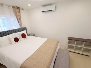Habitación de hotel con cama, mesitas de noche, aire acondicionado y mueble empotrado.