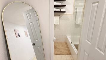 A bathroom with a toilet, a bathtub, and a shower area.