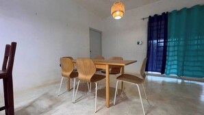 A dining area with a wooden table and chairs, a hanging light fixture, a door, and a window with curtains. - Tranquil Villa Retreat in Las Terrenas - Pet-friendly Haven (Las Terrenas)