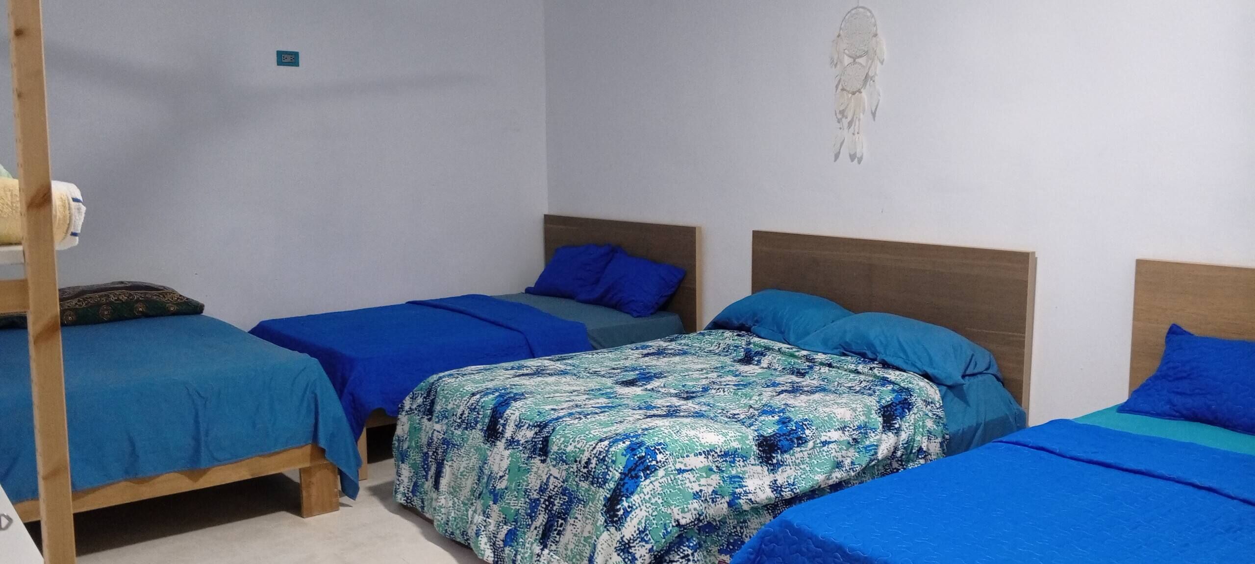 A room with three beds, each with blue bedding, and a wooden headboard.