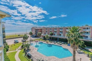 A hotel with a swimming pool, a beach view, and a multi-story building. - Coastal Oasis 1BR/1BA condo - Just steps from the Beach (Galveston)