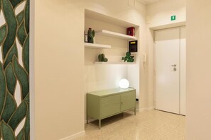 A hallway with a green cabinet, a white door, and a shelf with decorative items. - Four-Bedroom Holiday Home (Roma)