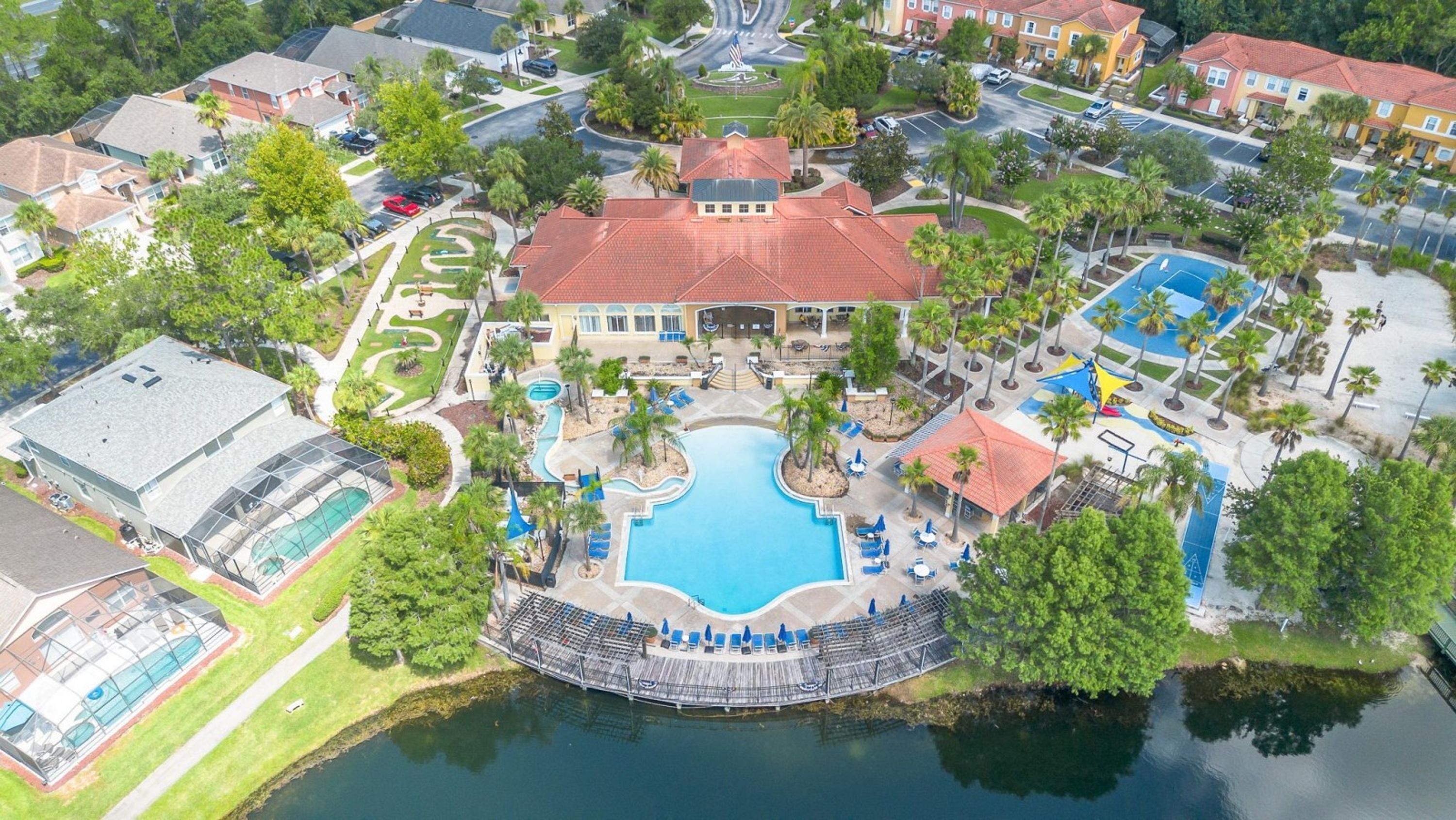 Luchtfoto van een resort met een centraal zwembad, een overdekt buitengebied en een waterpartij.