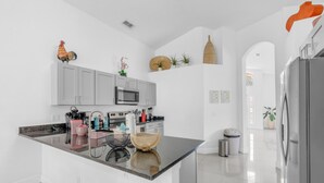 A modern kitchen with grey cabinets, a central island, and a stainless steel refrigerator. - Beautiful 4bdr With Private Pool Gated Community (Almont)