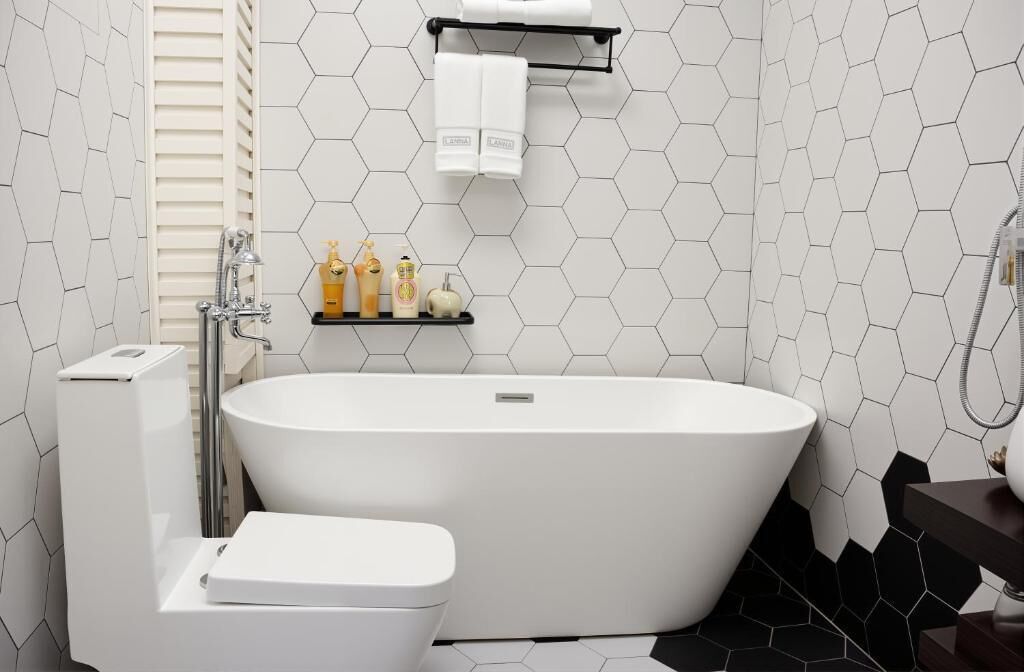 A modern bathroom with a freestanding bathtub, a toilet, and a shelf with toiletries.