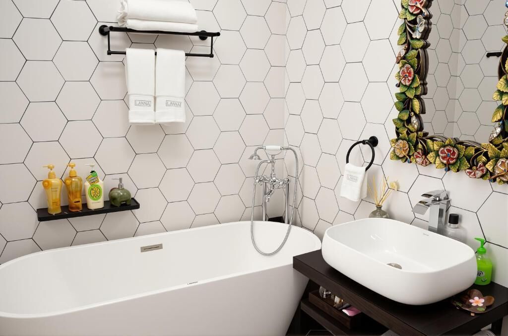 A modern bathroom with a white bathtub, a sink, and a mirror with a floral design.