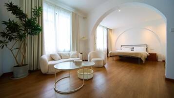 Un dormitorio moderno con cama, sofá, sillón y una mesa de centro.