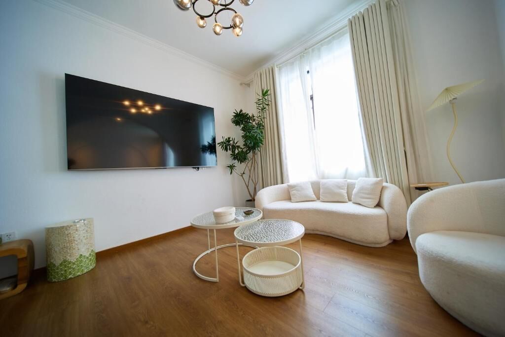 A modern living room with a flat-screen TV mounted on the wall, a sofa, a coffee table, and a floor lamp.