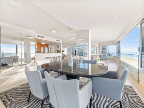 Ein modernes Interieur mit einem runden Tisch, grauen Stühlen und Blick auf den Ozean.