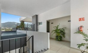 A modern hotel interior with a staircase, a view of the city, and a fire extinguisher on the wall. - Modern Apartment with a Pool (Puerto Vallarta)