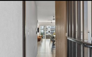 Um corredor que dá para uma sala de jantar com vista para um edifício residencial.